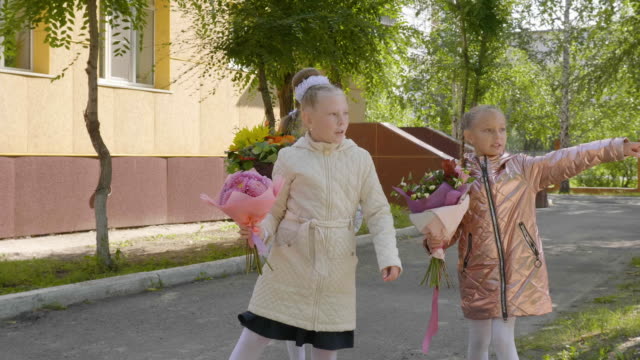 Drei-SchülerInnen-mit-Blumensträußen-irgendwo-mit-den-Fingern-zeigen