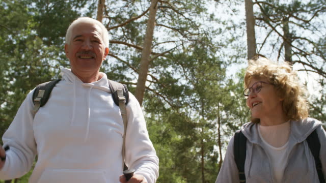 Adultos-mayores-felices-con-bastones-de-Trekking-disfrutando-de-caminata