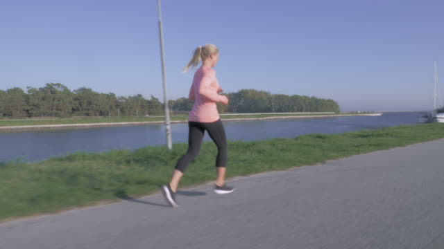 Frau-an-einem-Kanal-entlang-joggen
