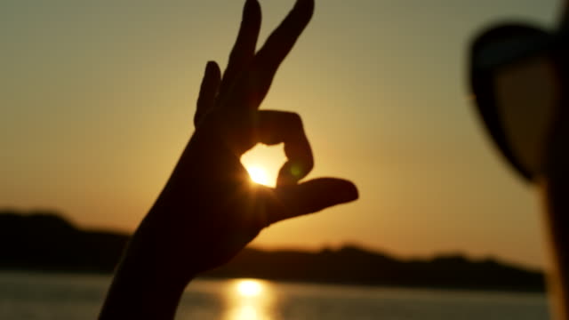 Silhouette-Of-Woman-Making-Shapes-With-Hands-Against-Sun