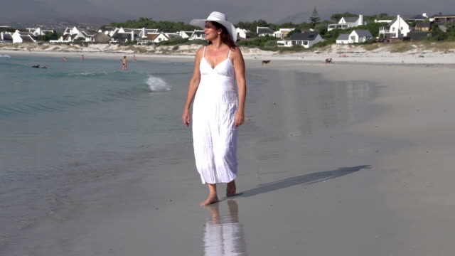 Woman-walking-along-the-water-line-on-the-beach,-Cape-Town,South-Africa