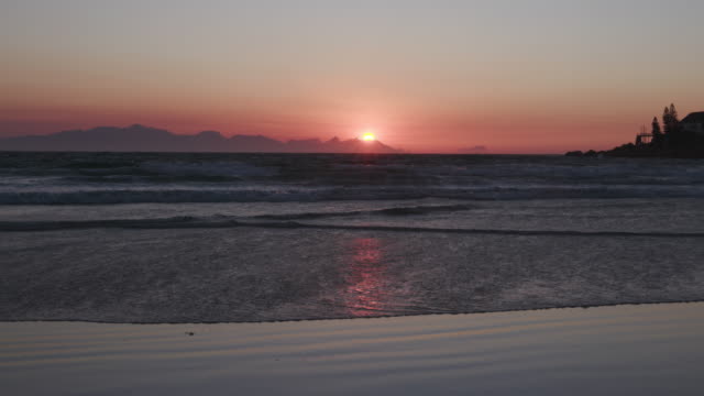 Un-amanecer-sobre-la-playa-en-Ciudad-del-Cabo,-Sudáfrica