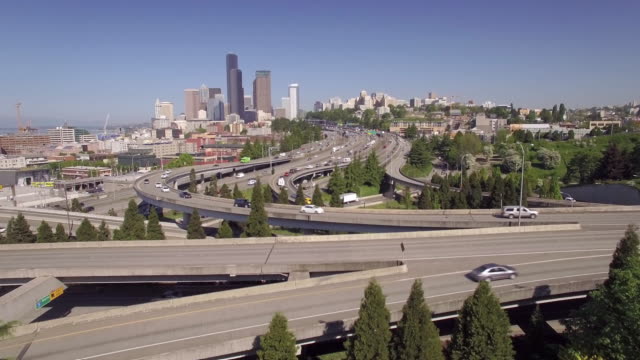 Freistil-Springen-in-Zeitlupe-fliegen-über-den-Freeway-in-die-Innenstadt-von-Seattle-bieten-einen-Wolkenkratzer-Gebäude-Skyline-auf-sonniger-Tag