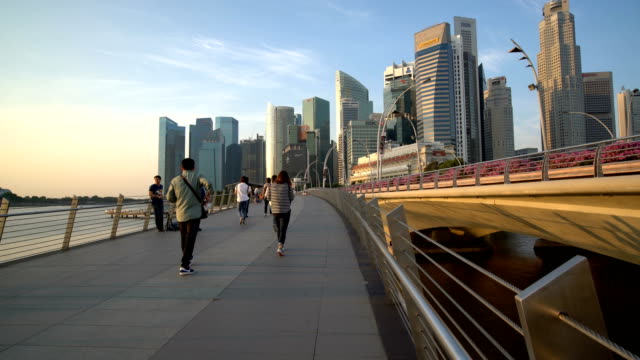 Personas-caminando-en-Marina-Bay,-Singapur-con-rascacielos-como-telón-de-fondo