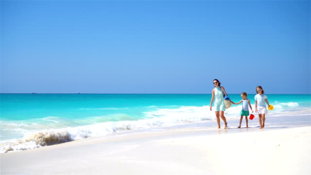 Family-of-mother-and-kids-walking-on-white-beach