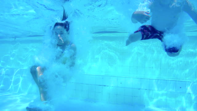 Unterwasseraufnahmen-der-Kinder-springen-und-Tauchen-im-Schwimmbad