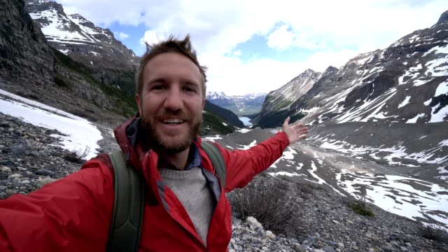 Young-cheerful-man-hiking-on-glacier-takes-selfie-portrait