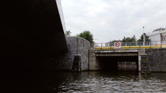 Filmación-de-las-calles-de-Amsterdam-y-las-aguas-del-Canal-mientras-se-desliza-debajo-de-un-puente
