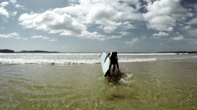 4K-\"Wellenlinien\"-Aufnahmen-von-jungen-Mann-ins-Meer-läuft-mit-alten-Surfbrett