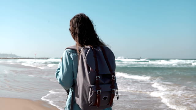 Girl-walks-on-summer-sea-beach-thinking-about-life.-Freedom-and-retreat-concept.-Wind-blowing-in-hair.-Amazing-sky.-4K