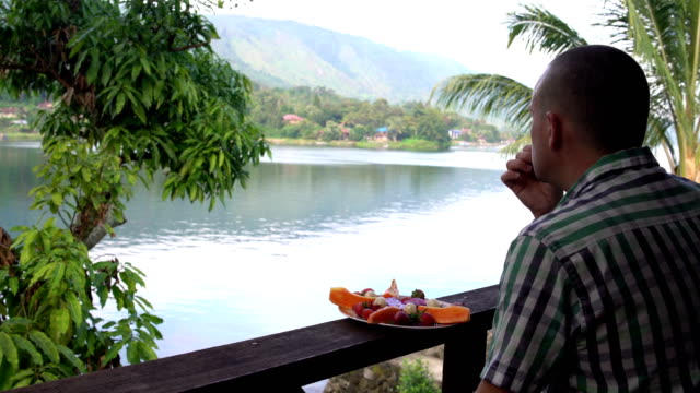 A-man-eats-strawberries-and-looks-at-the-lake-and-mountains