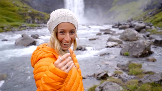 Folgen-Sie-mir-in-den-Wasserfall-junge-Frau-winkt-Freund,-Freundin-führender-Mann,-verliebt-sich-in-Island-Menschen-reisen-Konzept-Zeitlupe