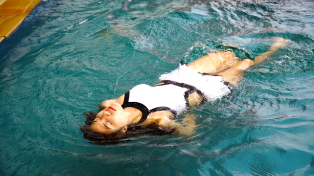Schöne-asiatische-Mädchen-im-Pool-In-weißen-Badeanzug.-Sie-schwimmt-mit-einem-Rücken.