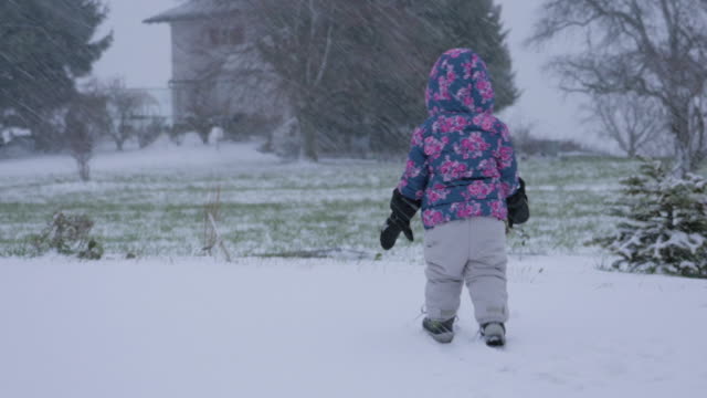 Kleinkind-zu-Fuß-in-einem-verschneiten-Hinterhof