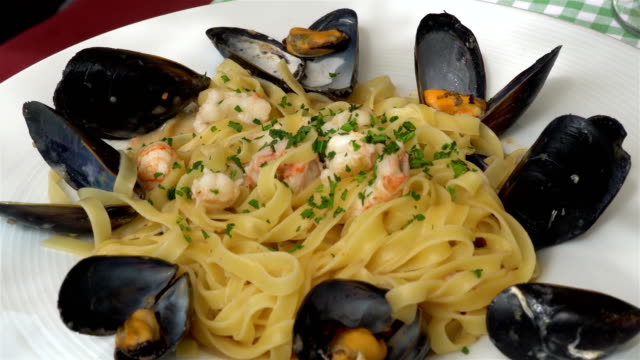 Traditional-mediterranean-pasta-with-mussels-and-seafood-on-a-traditional-Mediterranean-plate-garnished-with-summer-vegetables-and-fruits---greece,-croatia,-italy,-montenegro,-squid.