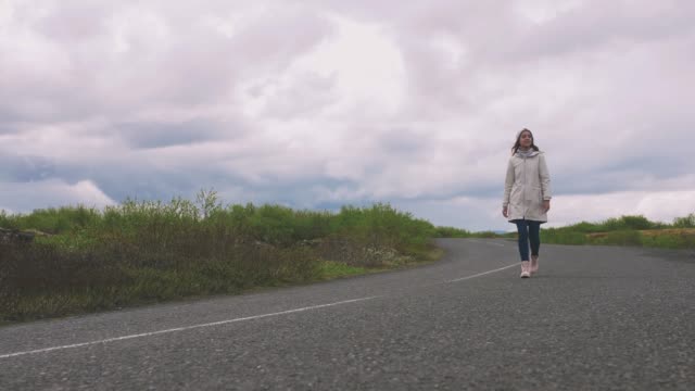 Young-woman-treveler-walks-on-the-road-of-Iceland,-the-Golden-ring-way