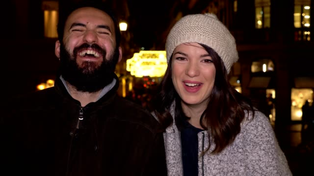 smiling-couple-laughing-in-street-at-winter-night,looking-camera-slow-motion