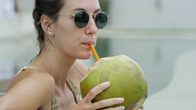 Mujer-en-gafas-de-sol-bebiendo-agua-de-coco
