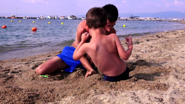 Joven-padre-con-un-hijo-pequeño-en-una-playa-de-mar,-Grecia