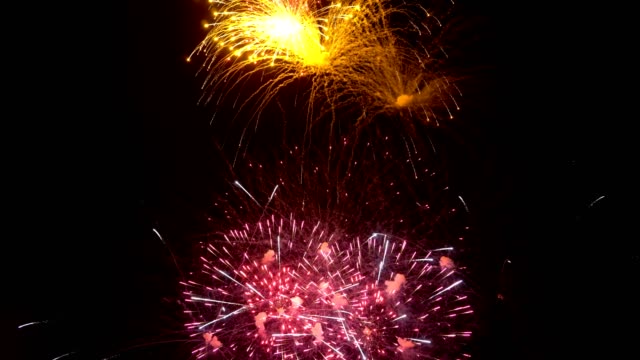 Fireworks-show.-Beautiful-yellow,-red-and-lilac-flashes-in-the-night-sky-on-a-black-background.