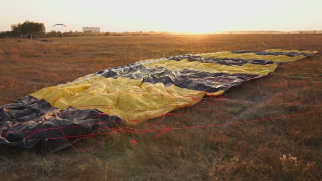 Paracaídas-en-el-suelo-de-los-rayos-del-atardecer-del-sol-en-el-campo-de-aviación