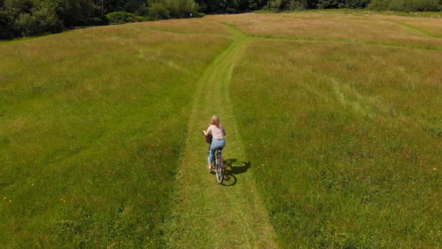 Woman-riding-bicycle-in-green-field-4k