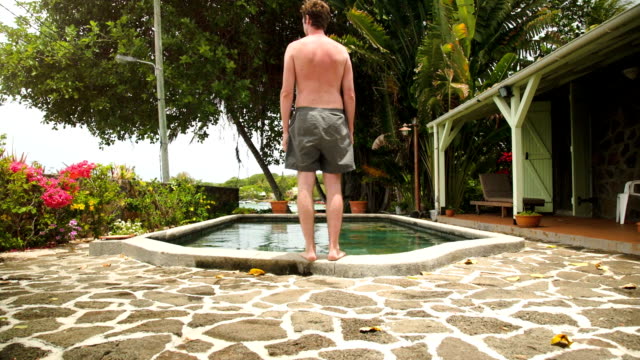 Hombre-salto-en-piscina-en-una-isla-tropical