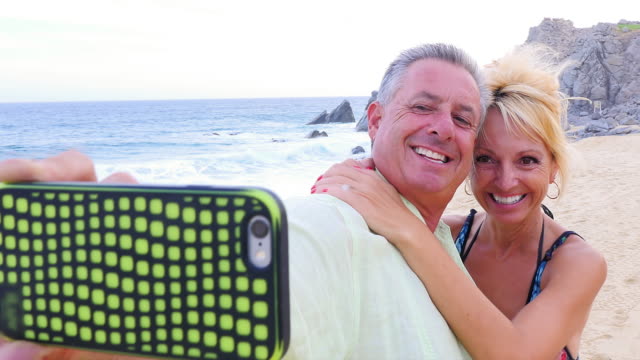 Eine-ältere-paar-Spaß-haben-und-nimmt-selfies-am-Strand