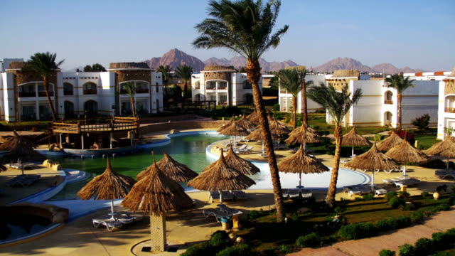 Sunny-Hotel-Resort-mit-blauen-Pool,-Palmen-und-Sonnenliegen-in-Ägypten