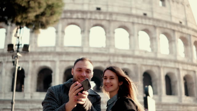 Joven-pareja-feliz-viajando-en-Roma,-Italia.-Hombre-y-la-mujer-tomando-la-foto-selfie-en-smartphone-cerca-del-Coliseo