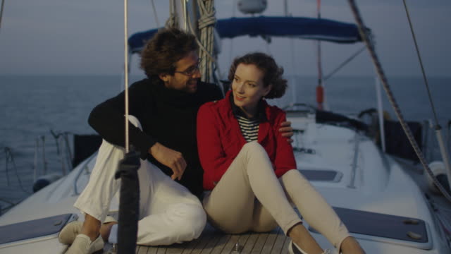 Young-couple-relaxing-on-a-yacht-in-the-sea-in-the-evening-at-sunset.