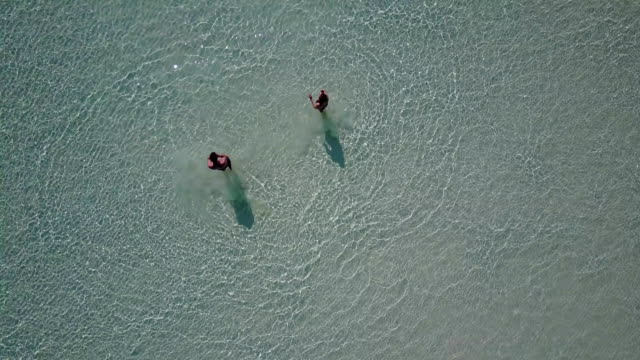 v03808-fliegenden-Drohne-Luftaufnahme-der-Malediven-weißen-Sandstrand-am-sonnigen-tropischen-Inselparadies-mit-Aqua-blau-Himmel-Meer-Wasser-Ozean-4k-2-Personen-junges-Paar-Mann-Frau-Ball-Spaß-zusammen-zu-spielen