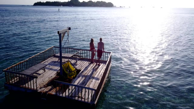 v03854-fliegenden-Drohne-Luftaufnahme-der-Malediven-weißen-Sandstrand-2-Personen-junges-Paar-Mann-Frau-entspannend-auf-sonnigen-tropischen-Inselparadies-mit-Aqua-blau-Himmel-Meer-Wasser-Ozean-4k-schwimmenden-Ponton-Steg-Sonnenbaden-zusammen