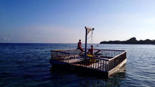v03827-fliegenden-Drohne-Luftaufnahme-der-Malediven-weißen-Sandstrand-2-Personen-junges-Paar-Mann-Frau-entspannend-auf-sonnigen-tropischen-Inselparadies-mit-Aqua-blau-Himmel-Meer-Wasser-Ozean-4k-schwimmenden-Ponton-Steg-Sonnenbaden-zusammen