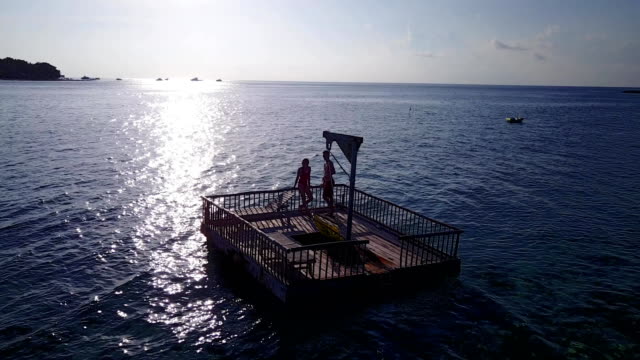 v03842-fliegenden-Drohne-Luftaufnahme-der-Malediven-weißen-Sandstrand-2-Personen-junges-Paar-Mann-Frau-entspannend-auf-sonnigen-tropischen-Inselparadies-mit-Aqua-blau-Himmel-Meer-Wasser-Ozean-4k-schwimmenden-Ponton-Steg-Sonnenbaden-zusammen