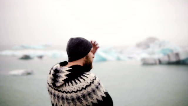 Young-bearded-man-standing-in-Jokulsalon-ice-lagoon-and-looking-on-glaciers,-North-nature-in-Iceland