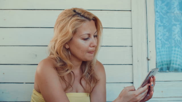 Mujer-rubia-escribir-mensaje-por-teléfono-móvil-y-descansando-en-la-terraza-de-verano
