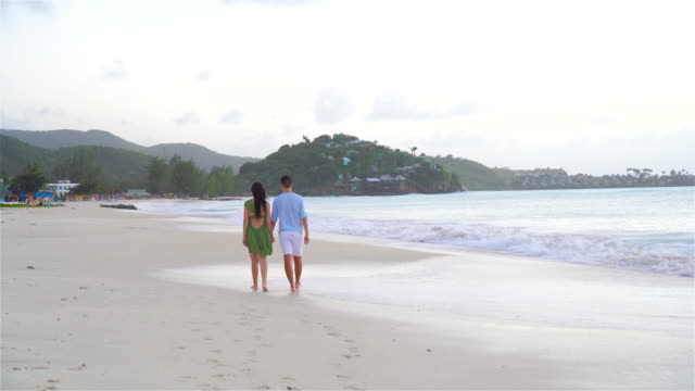 Young-couple-on-white-beach-during-summer-vacation.-Happy-family-enjoy-their-honeymoon