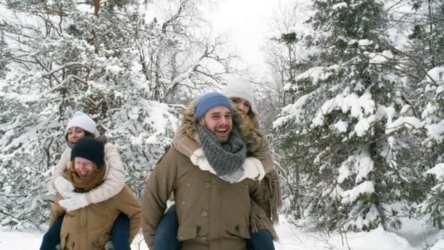 Junge-Paare-Huckepack-Reiten-im-verschneiten-Wald