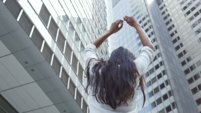Young-Woman-Dancing-Under-Financial-District-Skyscrapers