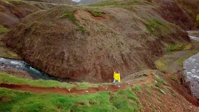 Amazing-drone-point-of-view-of-woman-hiking-on-mountain-ridge-over-canyon-in-Iceland.