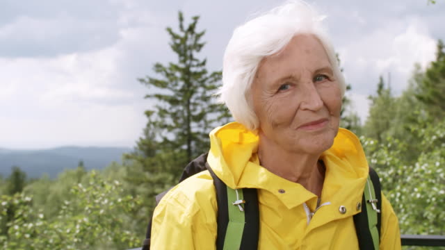 Positiven-Senior-Woman-Posing-auf-Sicht-in-Bergen