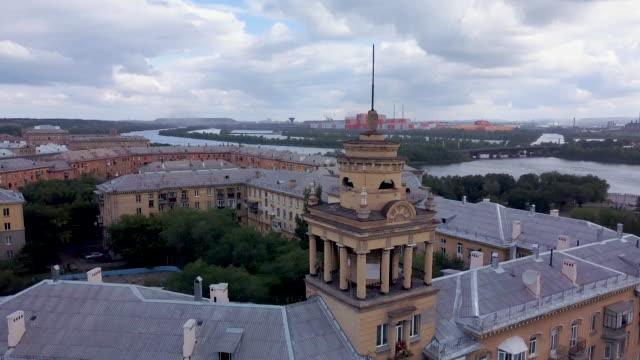 Drone-flight-near-the-old-style-tower-with-factory-on-the-background