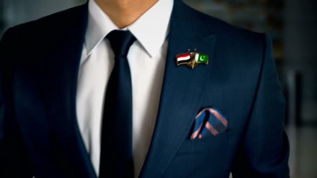 Businessman-Walking-Towards-Camera-With-Friend-Country-Flags-Pin-Egypt---Pakistan