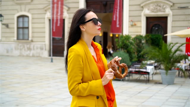 Beautiful-young-woman-holding-pretzel-and-relaxing-in-park