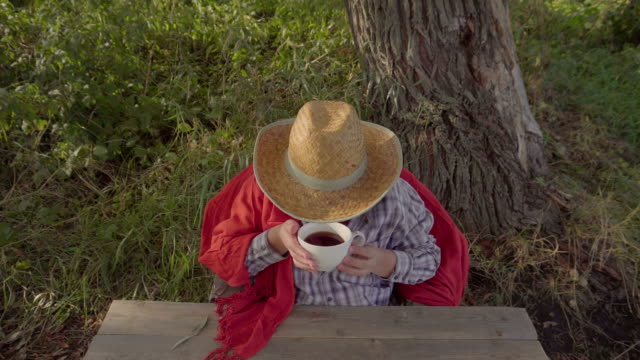 Eine-Frau-in-einem-Strohhut-Tee-trinken