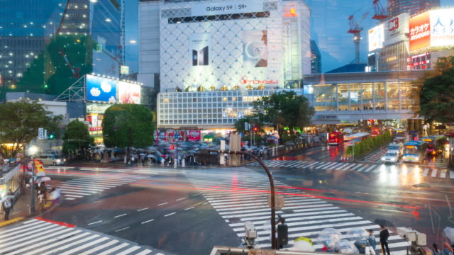 Shibuya-district-at-rainy-day-with-crowd-passing-crosswalk.-Tokyo,-Japan.-view-through-window.-4K-Timelapse.