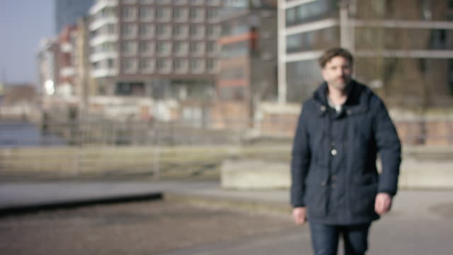 Middle-aged-man-in-a-winter-jacket-walking-towards-the-camera-in-urban-surrounding.