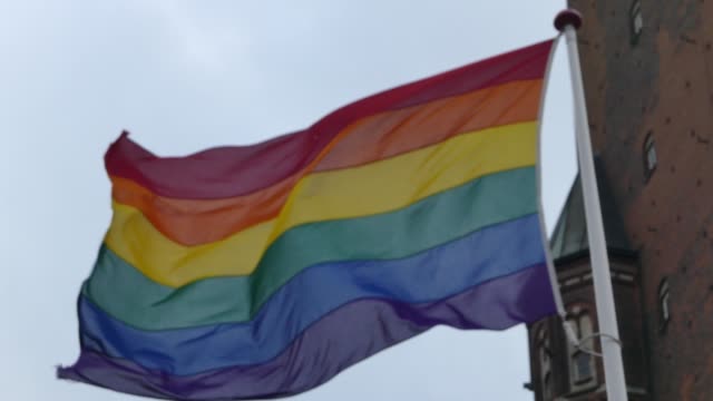 Bandera-de-arco-iris-en-el-centro-de-la-ciudad.-Bandera-arcoíris-(movimiento-LGBT)-revoloteando-en-el-viento.-De-cerca.