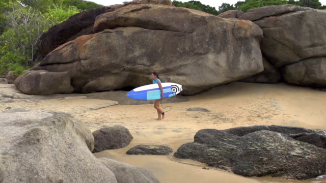 CÁMARA-LENTA:-Chica-surfista-caminando-por-el-agua